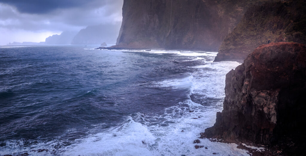 Miradouro do Guindaste Viewpoint Madeira - Moody Shot of Lonley Traveller - Drone Shot over Windy Ocean