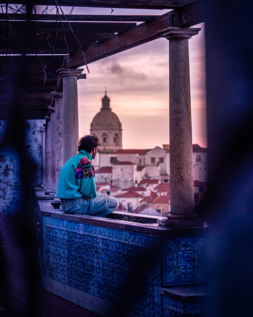 Miradouro de Santa Luzia - Best Sunrise Viewpoint in Lisbon Portugal - Traveller Sitting on Wall